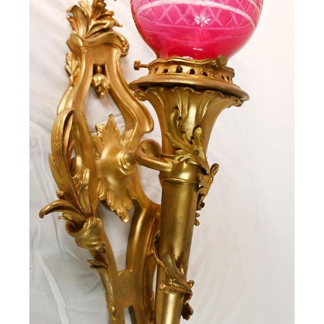 Elegant pair of french gilt bronze wall sconces in the louis xv revival taste each fitted with striking cranberry cut...