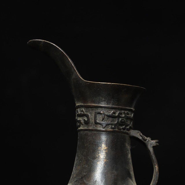 Stunning archaic-style bronze ritual wine vessel, known as a Palace Cup. It features three pointed tripod feet, a curved...