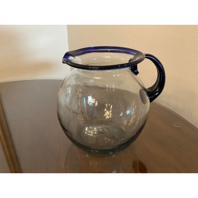 Vintage hand blown Mexican Glass Pitcher is trimmed in Cobalt Blue on the Rim and Handle. It is a beautiful piece of art...