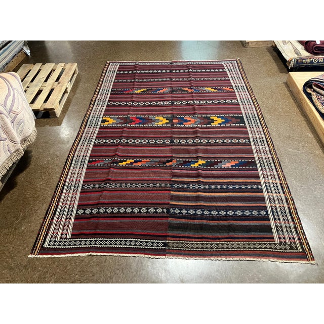 Handwoven Persian kilim flatweave rug featuring a wide striped field with horizontal bands of geometric and tribal motifs....