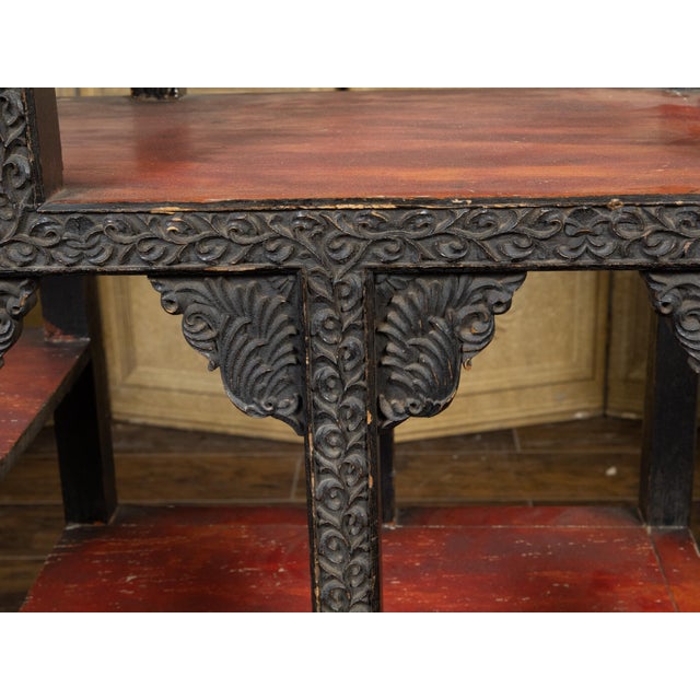 An Anglo-Indian tiered shelf from the early 20th century, with richly carved structure, scrolling foliage, reddish brown...