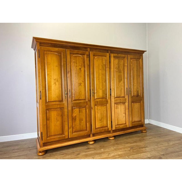 A substantial Vintage French wardrobe with a clean five-door design, raised panel fronts and a warm polished finish. The...