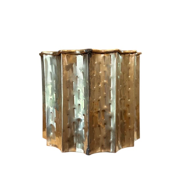 A sculptural, hammered brass cachepot/planter. Features a fluted form with dimpled texturing and a rolled rim. Circa 1950,...