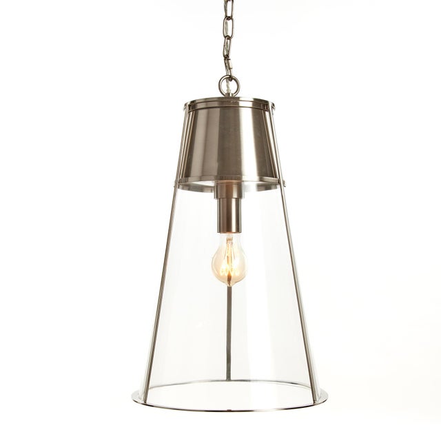 Generous in scale, and made of a modern mix of silver and glass, this pendant is a handsome fixture. Over an island, in an...