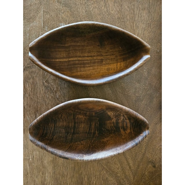 Sleek pair of hand carved wooden, boat shaped bowls. Sticker on the bottom says Haiti. Rustic yet modern style. The bowls...