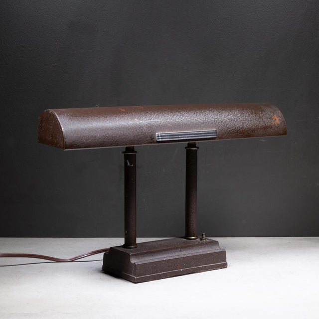 ABOUT A mid-century industrial banker's desk lamp featuring a textured brown metal finish, a tilting rectangular hood...
