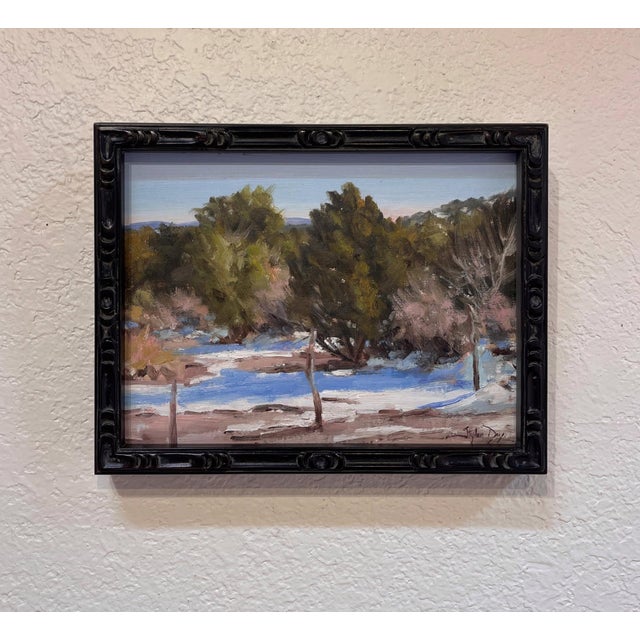 This oil painting captures a serene winter landscape, where sunlight filters through a canopy of trees, casting intricate...