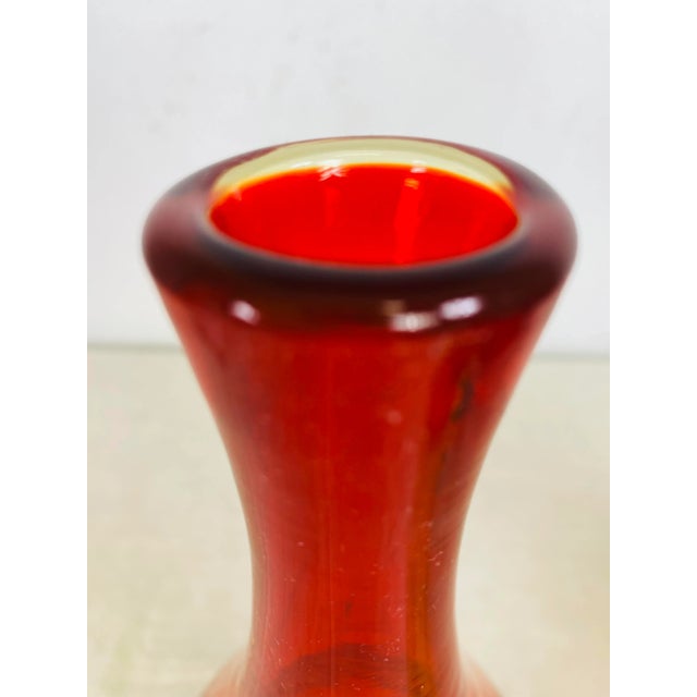 This is a mid century modern hand blown Amberina bud vase for Blenko by the designer Wayne Husted. Wayne Husted was the...