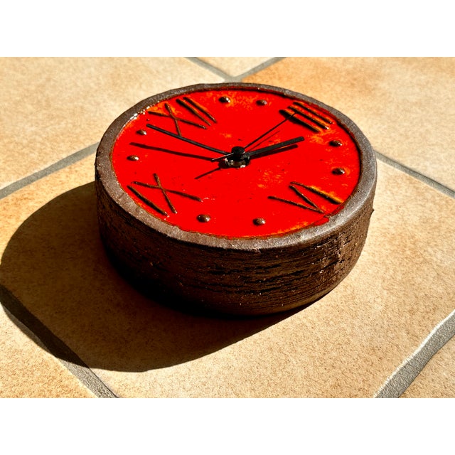 An impressive ceramic art wall clock in brutalist style with a rough charm and fat lava glaze in hues of orange-red. It...