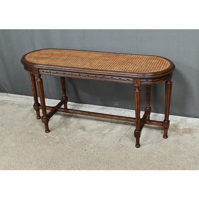 This walnut piano bench, in the refined Louis XVI style, embodies the timeless elegance of period furniture. Its oblong...