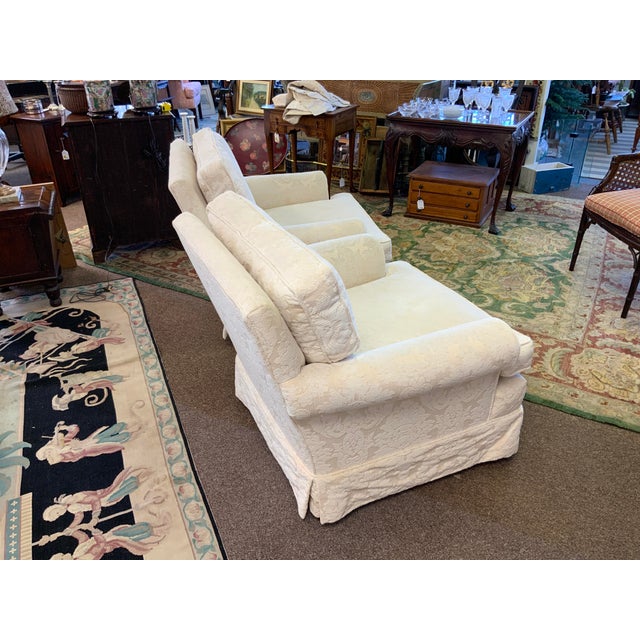 20th century pair of upholstered club chairs. Chenille fabric in a soft white tone floral pattern. Comfortable deep seat.
