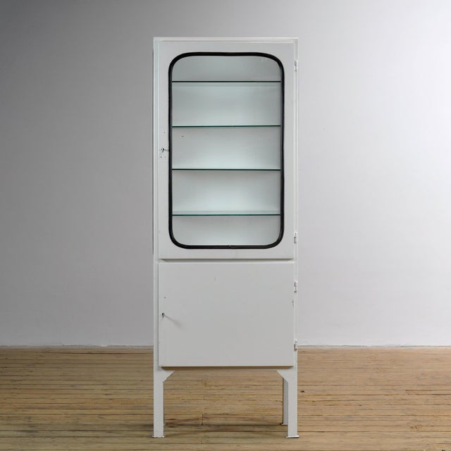 Vintage medicine cabinet from the 1970s, produced in Hungary. This cabinet is made of iron and glass, with the glass held...