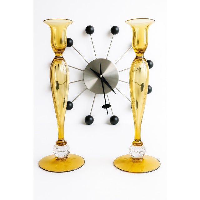 A striking pair of early 20th-century Pairpoint candlesticks in rich Honey Amber glass, accented by finely cut crystal orb...