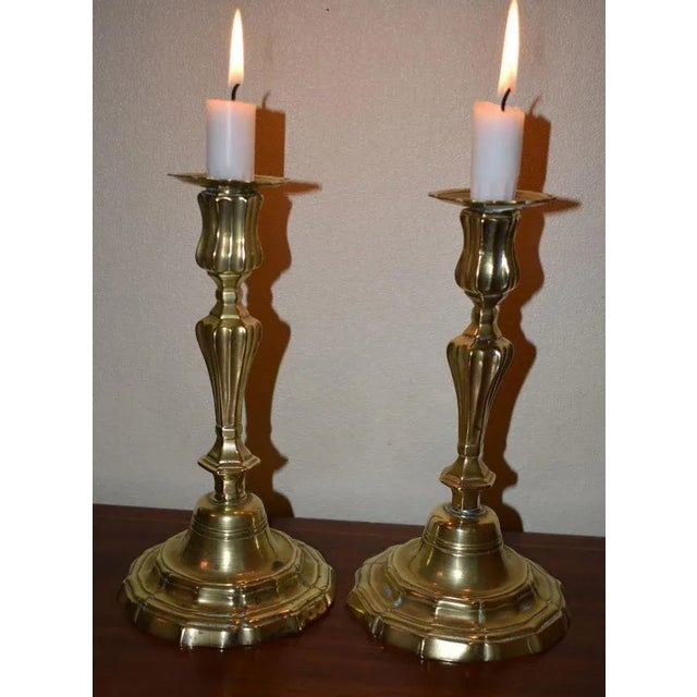 A pair of Louis XV candlesticks in baluster form with molded stems above stepped bases and serpentine rims. A bit more in...