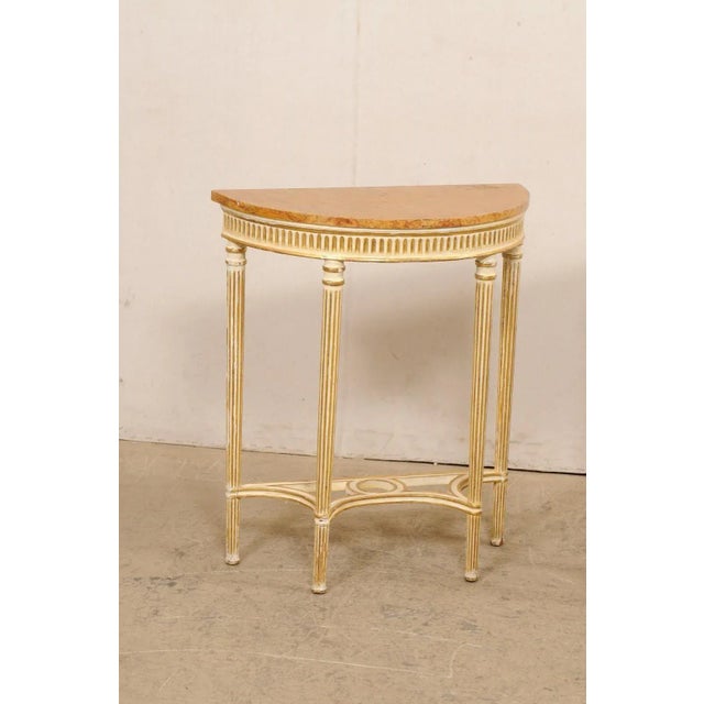 An Italian pair of flute-carved and painted wood demi lune tables from the early 20th century. These small-sized tables...