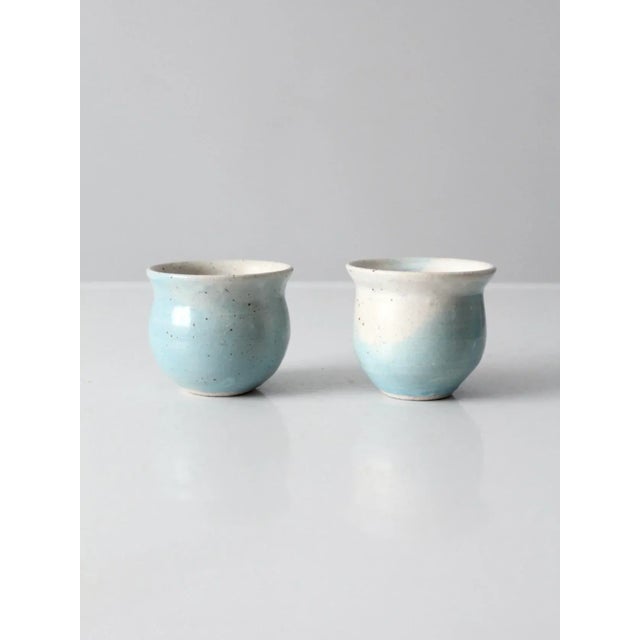 A pair of vintage studio pottery cachepots, hand-crafted in ceramic with a light blue and cream speckled glaze. Each...