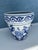 Vintage porcelain Chinoiserie planter features a distinctive blue and white floral motif with a decorative scroll border....