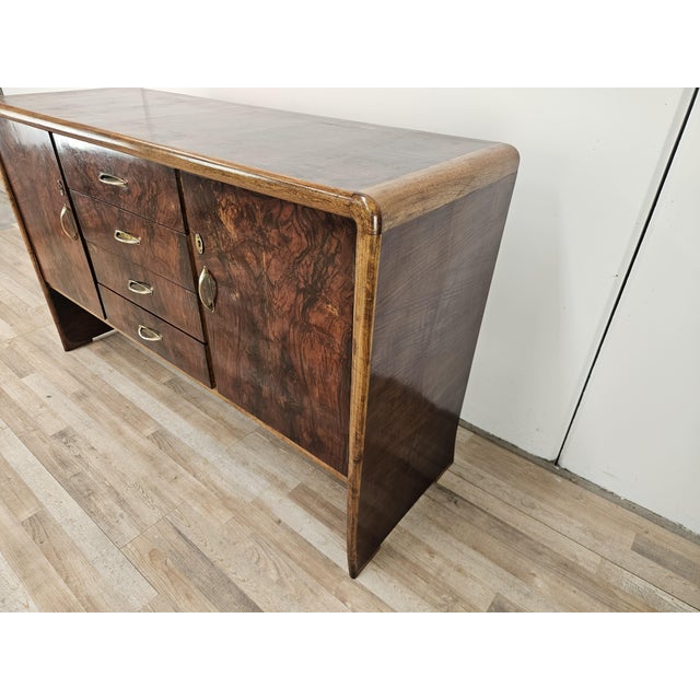 A 1950s Art Deco sideboard, crafted from fine walnut with elegant blond walnut inserts. This piece is striking for its...