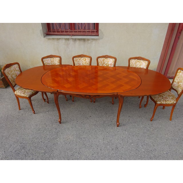 Large oval table seating 6 to 12 people thanks to the integrated extensions stored beneath the tabletop. Cherry-stained...