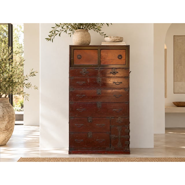 Sweeping red-orange grain fills the sliding doors of this tansu, each panel framed in black with a round recessed pull....