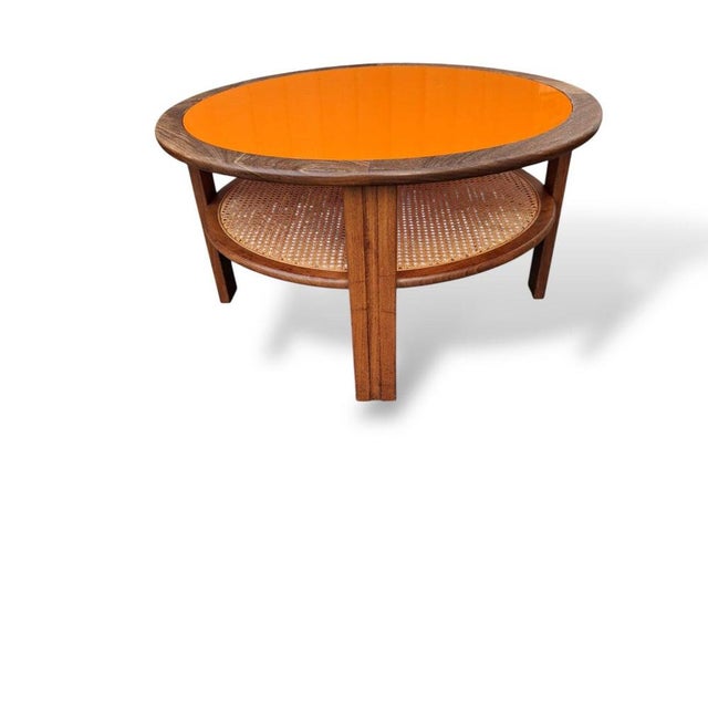 A striking mid-century round coffee table by G-Plan, featuring a bold orange acrylic inset top framed by warm-toned wood....