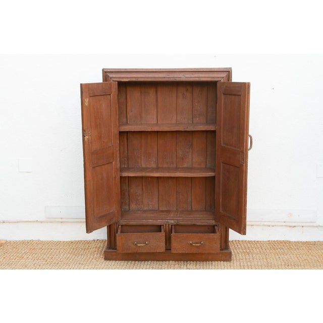 This 57-inch tall antique cabinet is a study in colonial geometry and texture. Crafted from solid teak, it features a...
