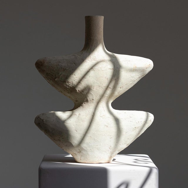 Two sharp, wing-like flanges extend outward in mirrored symmetry from this Tamegroute vase, a slender neck rising quietly...