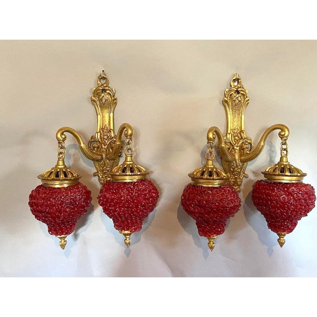 A striking pair of 1980s French Louis XVI-style gilded bronze wall sconces, beautifully designed with ornate bronze frames...
