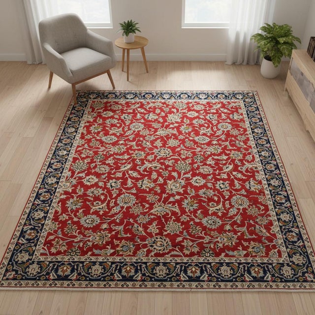 This Persian Isfahan Rug features a rich red field adorned with detailed floral motifs in shades of blue, gold, and ivory....