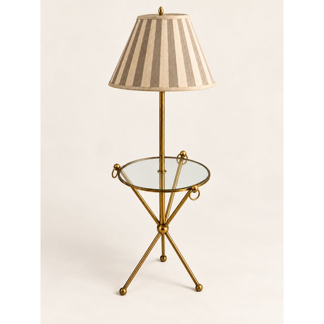 An unusual antique brass floor lamp with a circular glass shelf and custom vertically striped shade. Both sculptural and...