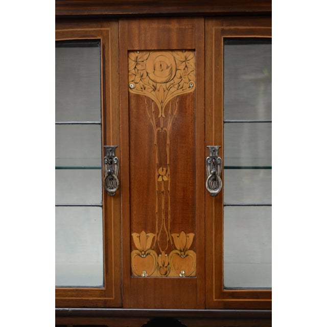 Art nouveau mahogany and marquetry hall cabinets, each having arched cresting above divided mirror flanked by a pair of...