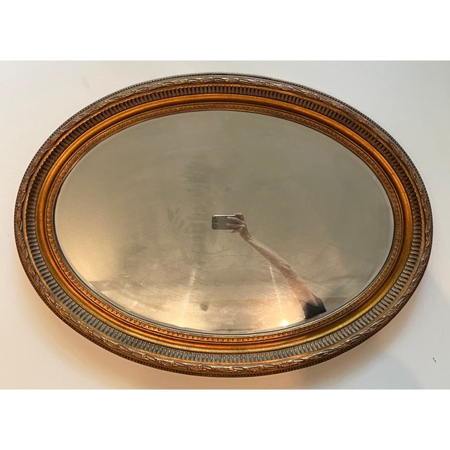 This elegant, large hand painted gold oval frame with a 1 inch beveled mirror is a classic example of a French style...