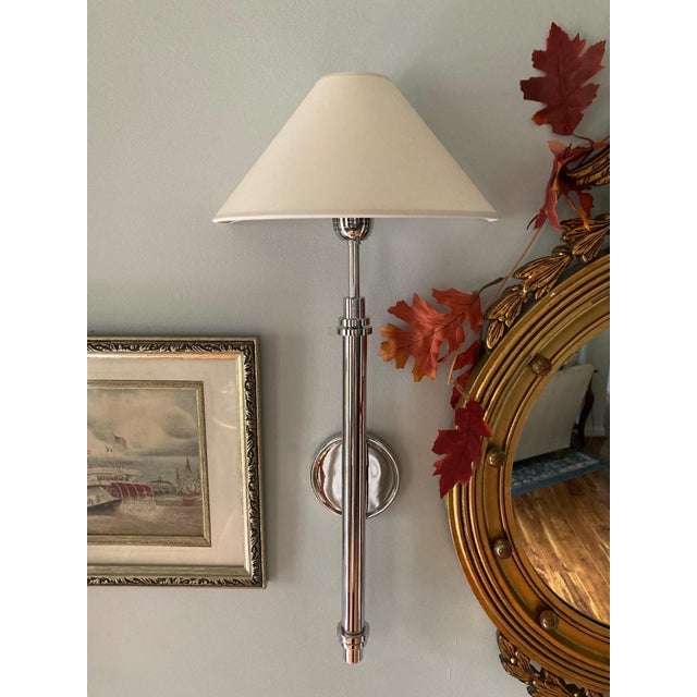 Designed by J. Randall Powers for Visual Comfort, the Hargett polished nickel wall sconce pairs a slender candlestick-...