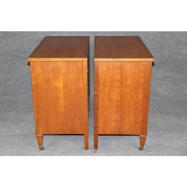A handsome and beautifully matched pair of Kindel French Directoire-style cherry nightstands, combining the restrained...