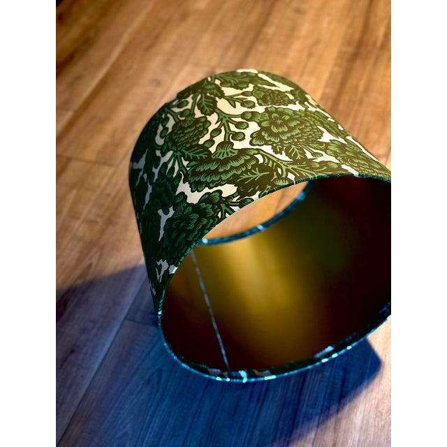 A richly patterned handmade lampshade in layered shades of emerald and forest green, featuring an exuberant botanical...