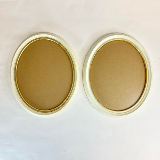 This pair of vintage painted wood framed oval picture frames are from Germany from the 1950s. Each has a glass insert and...
