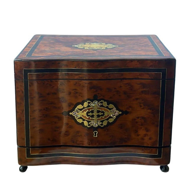 An elegant Napoleon III period Cave À Liqueur cabinet with burl wood case, inlaid brass and mother of pearl details. The...