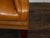 An English brown leather wingback chair from circa 1930-1940 with brass nailhead trim, tapered legs in the front and saber...