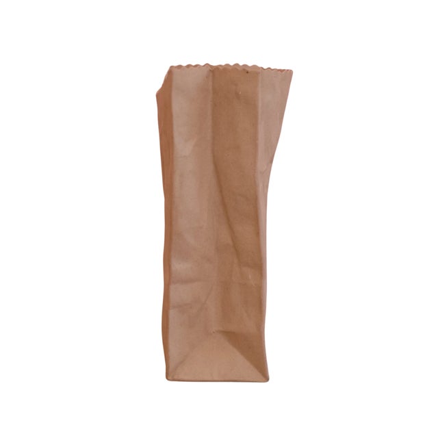 A delightfully unexpected trompe l’oeil ceramic vase modeled after a crumpled Michael Harvey paper bag — equal parts pop...
