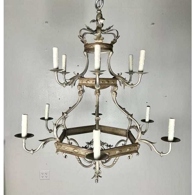 Monumental size 12-light, two-tiered silvered chandelier. The chandelier is adorned with a crown on top and cherub faces...