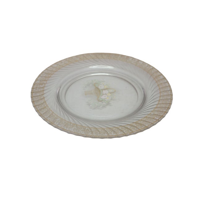 Mid century clear glass plate featuring an etched floral basket center motif and an gold patterned rim with a swirled...