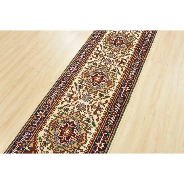 A traditional tribal Heriz runner hand-knotted with an all-wool pile on a cotton foundation. This oriental rug features a...