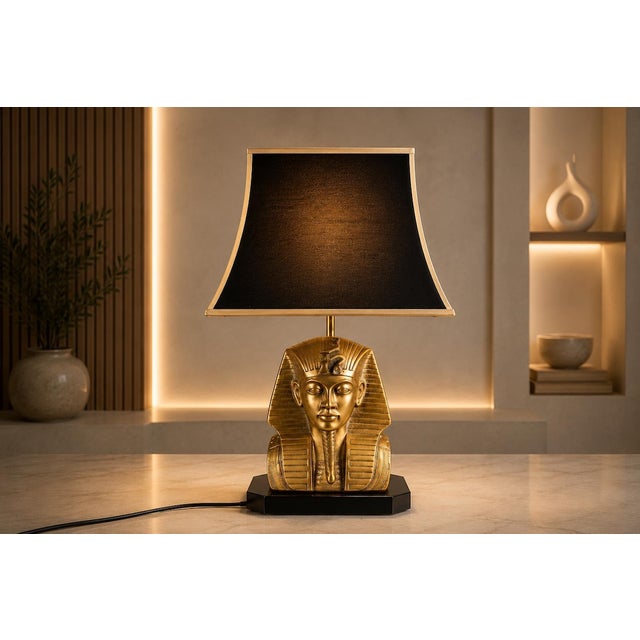 A bold and highly decorative vintage table lamp in the Egyptian Revival style, featuring a sculptural brass pharaoh bust...