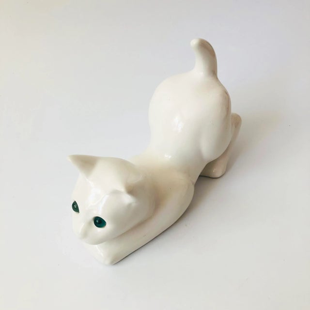 A vintage ceramic cat sculpture finished in a glossy white glaze with blue eyes. Made in Portugal by Elpa Alcobaca, marked...