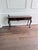 Queen Anne-style dark mahogany console table featuring two brass bail-handle drawers and graceful cabriole legs ending in...