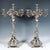 A pair of tall festive silver candelabra on a stepped funnel-shaped stand, based on four lion feet with volute and foliate...
