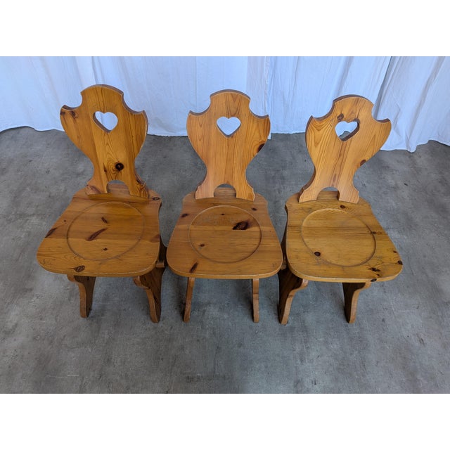 Set of 3 wooden chairs, that are made in a traditional Tyrolean style, featuring solid wood construction and heart-shaped...