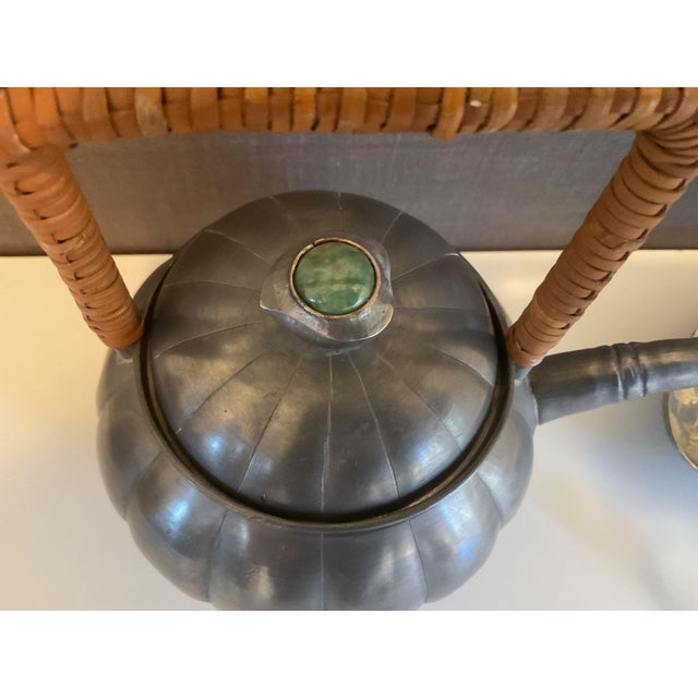 Elegant mid‑century Asian pewter teapot featuring a ribbed melon‑form body, rattan‑wrapped square handle, and jade‑style...