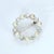 This circular brooch features alternating pearls and diamonds, creating a harmonious design. The pearls exhibit a soft...