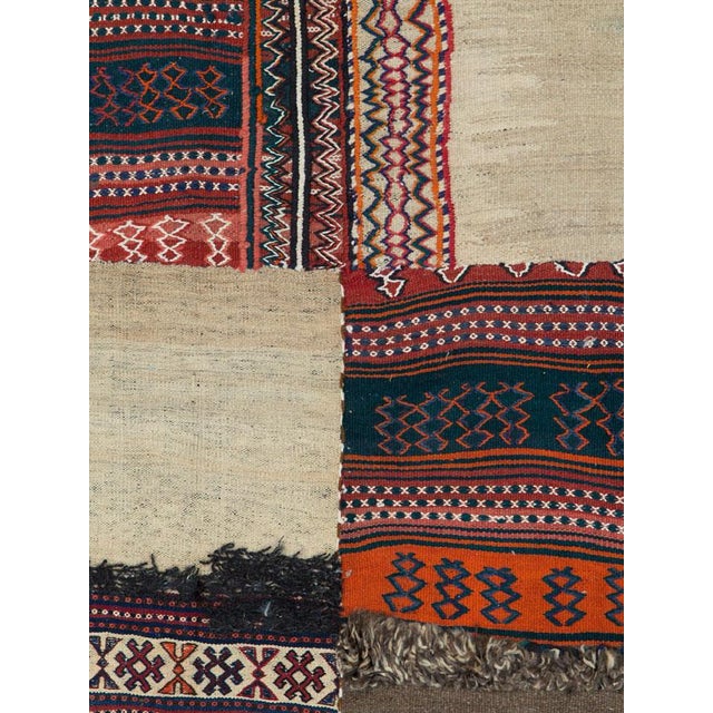 This Mid-20th century Persian flatweave kilim presents an engaging patchwork-style composition that reflects the...